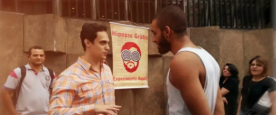 Demonstração de hipnose na rua, com o banner ao fundo. Acervo pessoal de Lucas Naves